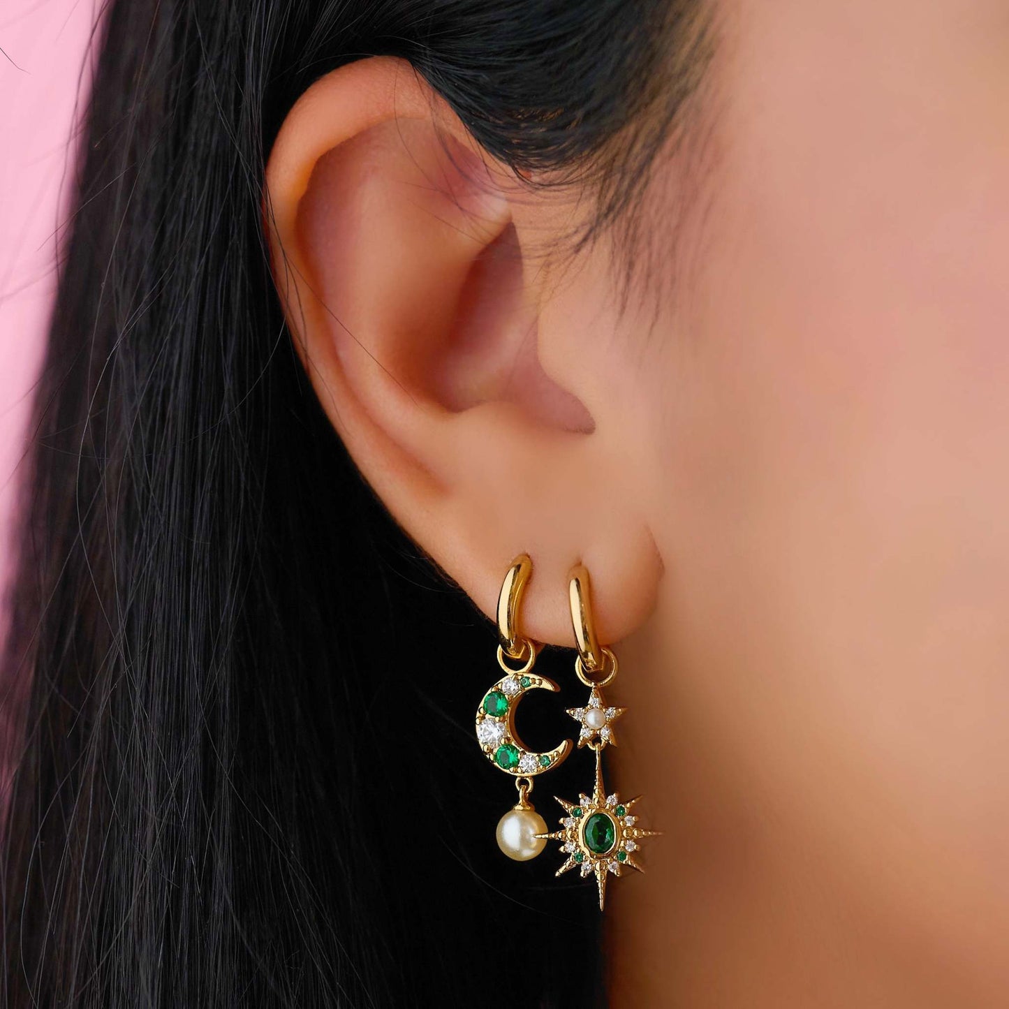 Moon & Star Huggie Hoop Earrings with emerald green crystals and moon and star charms, styled in a pierced ear