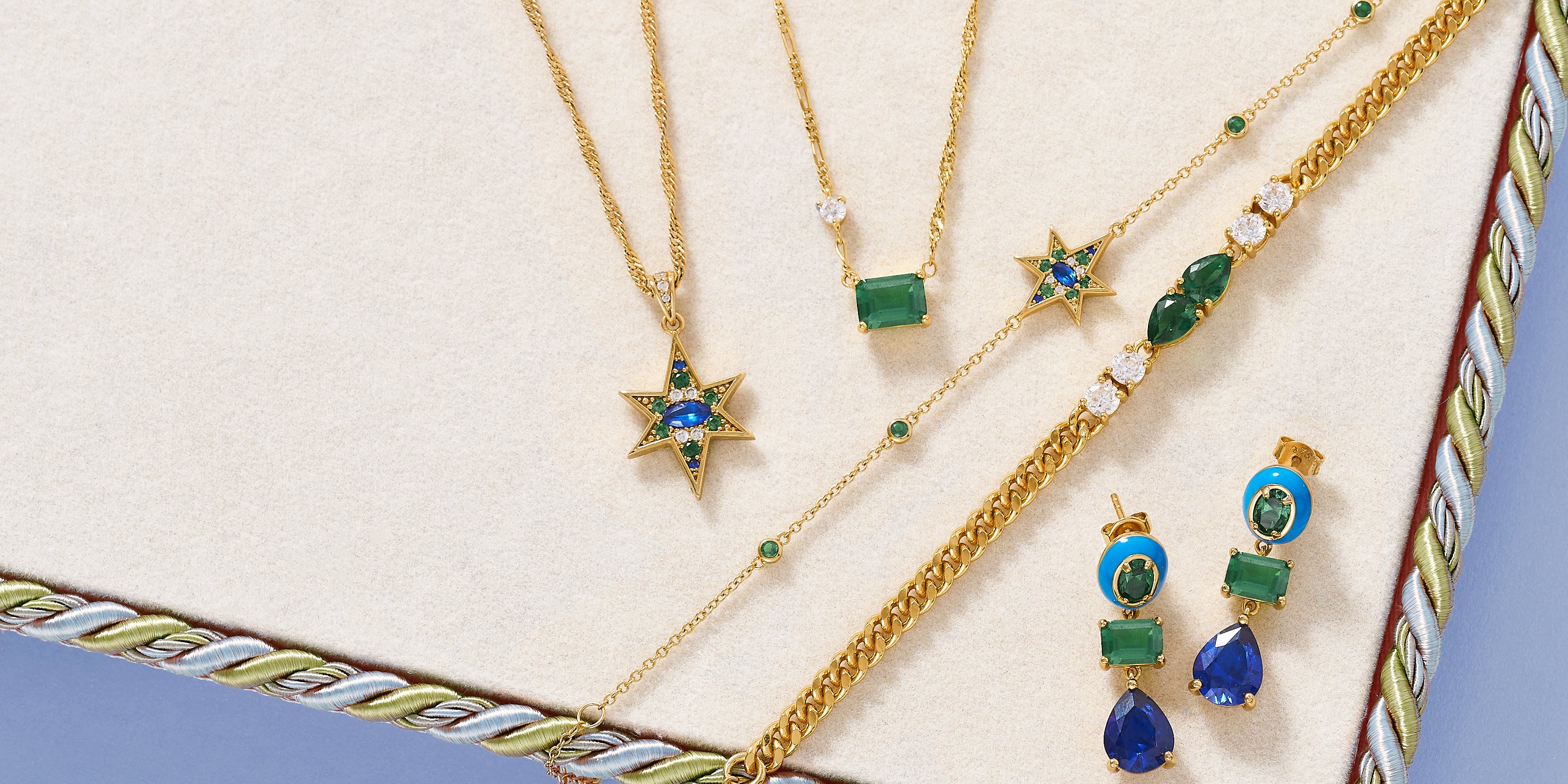 Gold star jewellery set with green and blue gemstones on a vintage style textured surface