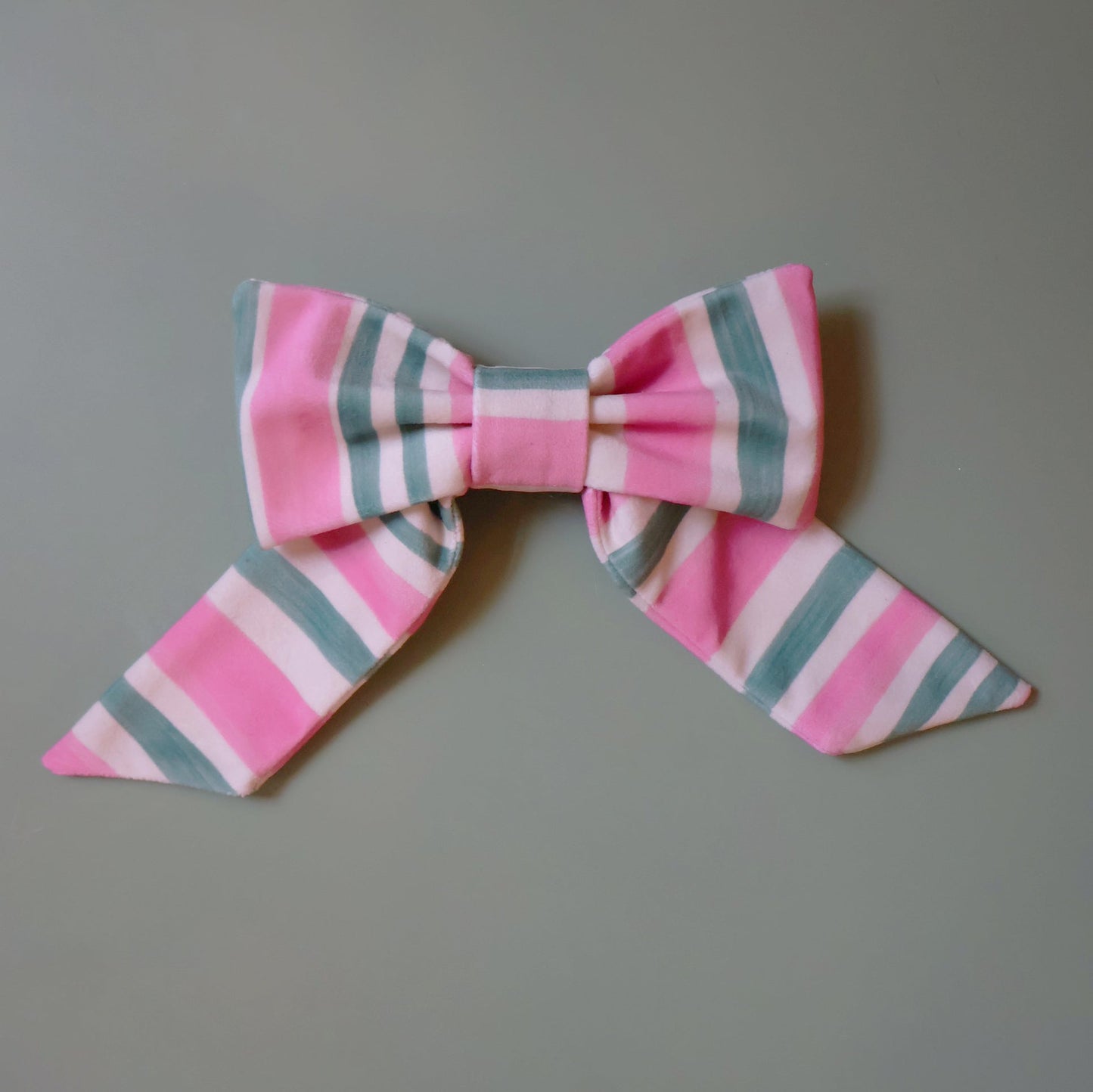 Pink and green striped velvet bow hair accessory with oversized candy stripe design and metal spring barrette clip