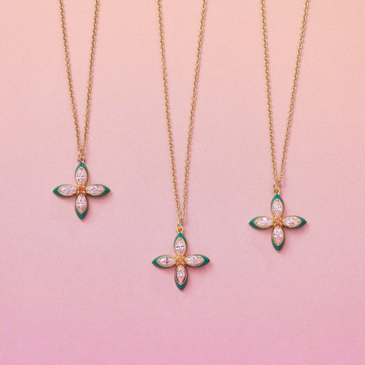 Three Lucky Clover Pendant Necklaces with emerald enamel and lab grown cubic zirconia on gold chains against pink background
