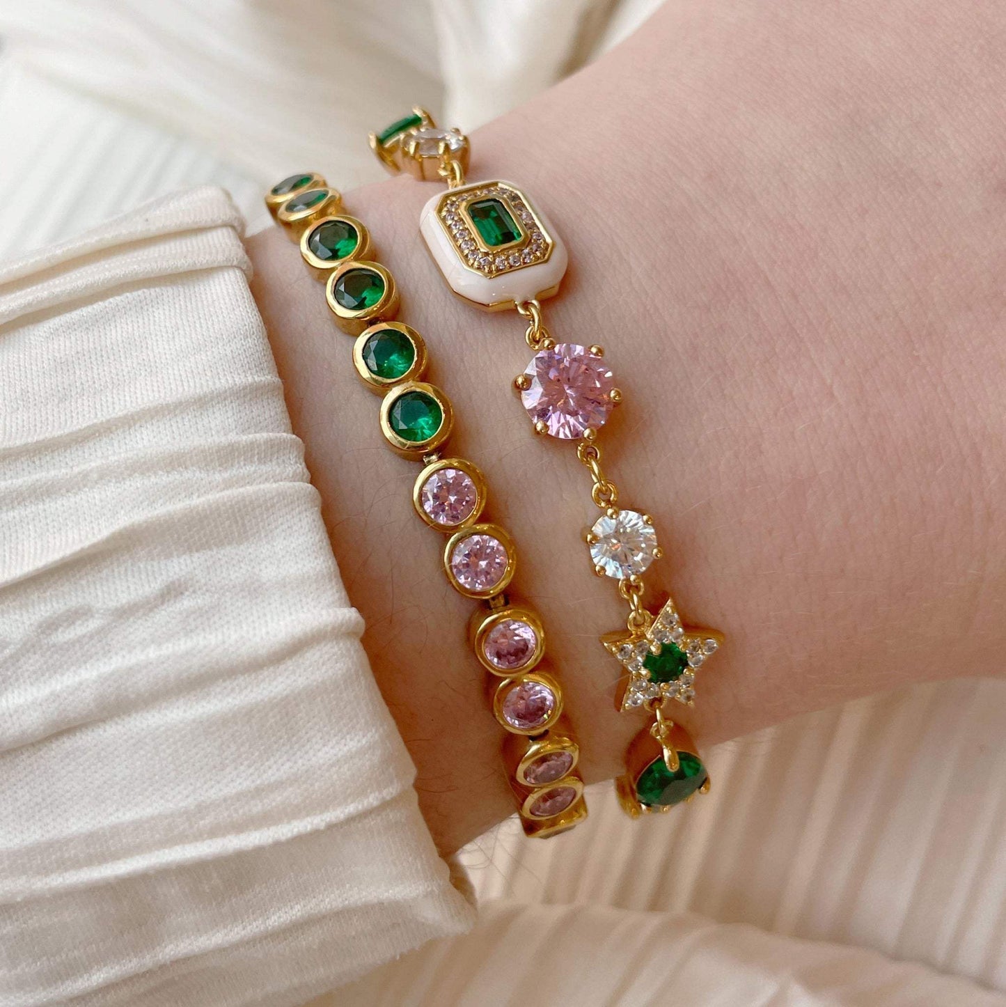 Bracelet set with blush pink enamel, emerald green stones, and gold plating on wrist
