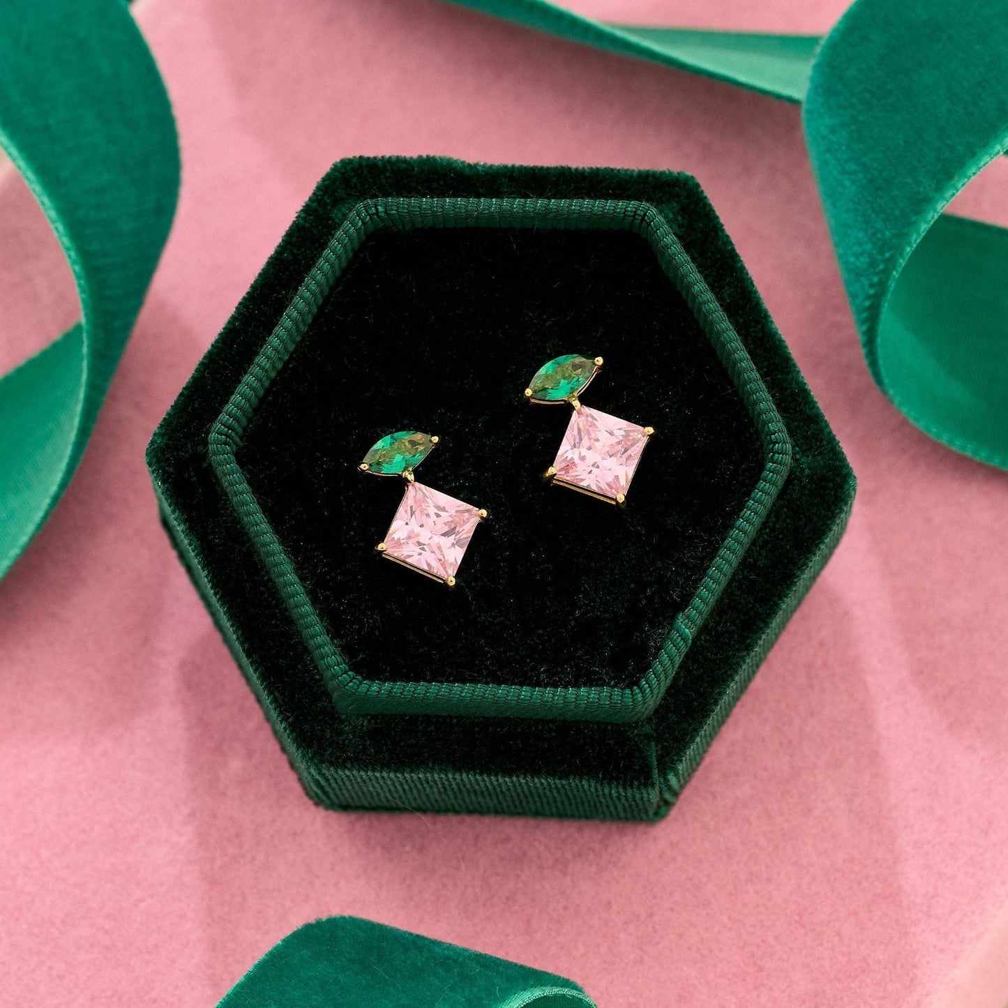 Unusual gold earrings. Shop colourful emerald green and pink cubic zirconia stud earrings in 18k gold plated recycled sterling silver displayed in a green velvet hexagonal box.