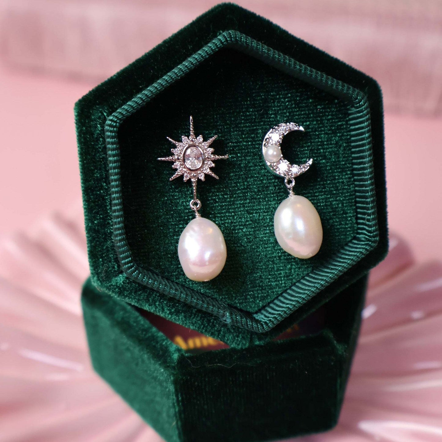 Silver pearl star earrings in a green jewellery box on a pink background