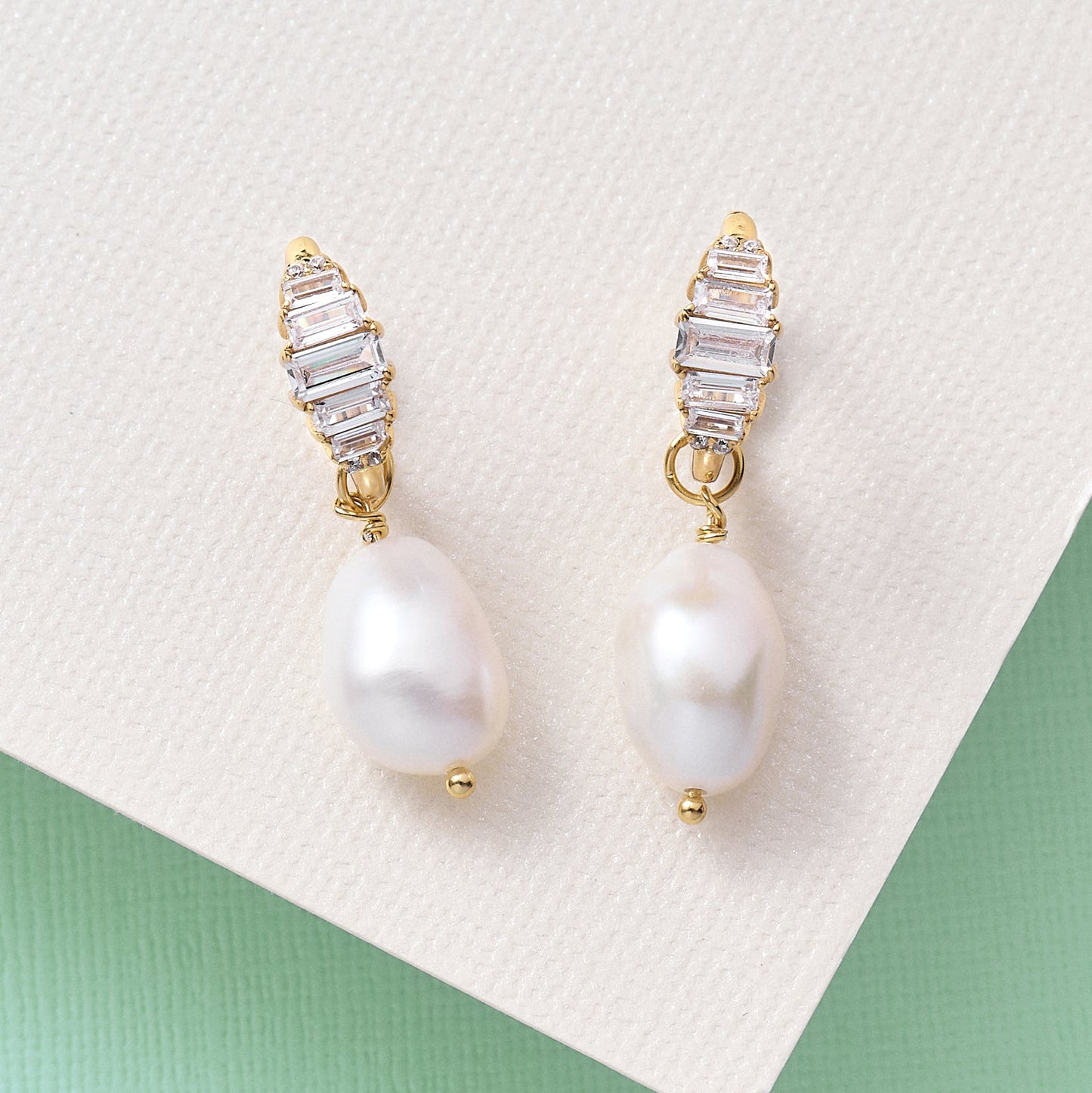 Isla Art Deco hoop earrings with gold plating, lab-grown cubic zirconia, and detachable baroque pearls on a textured background