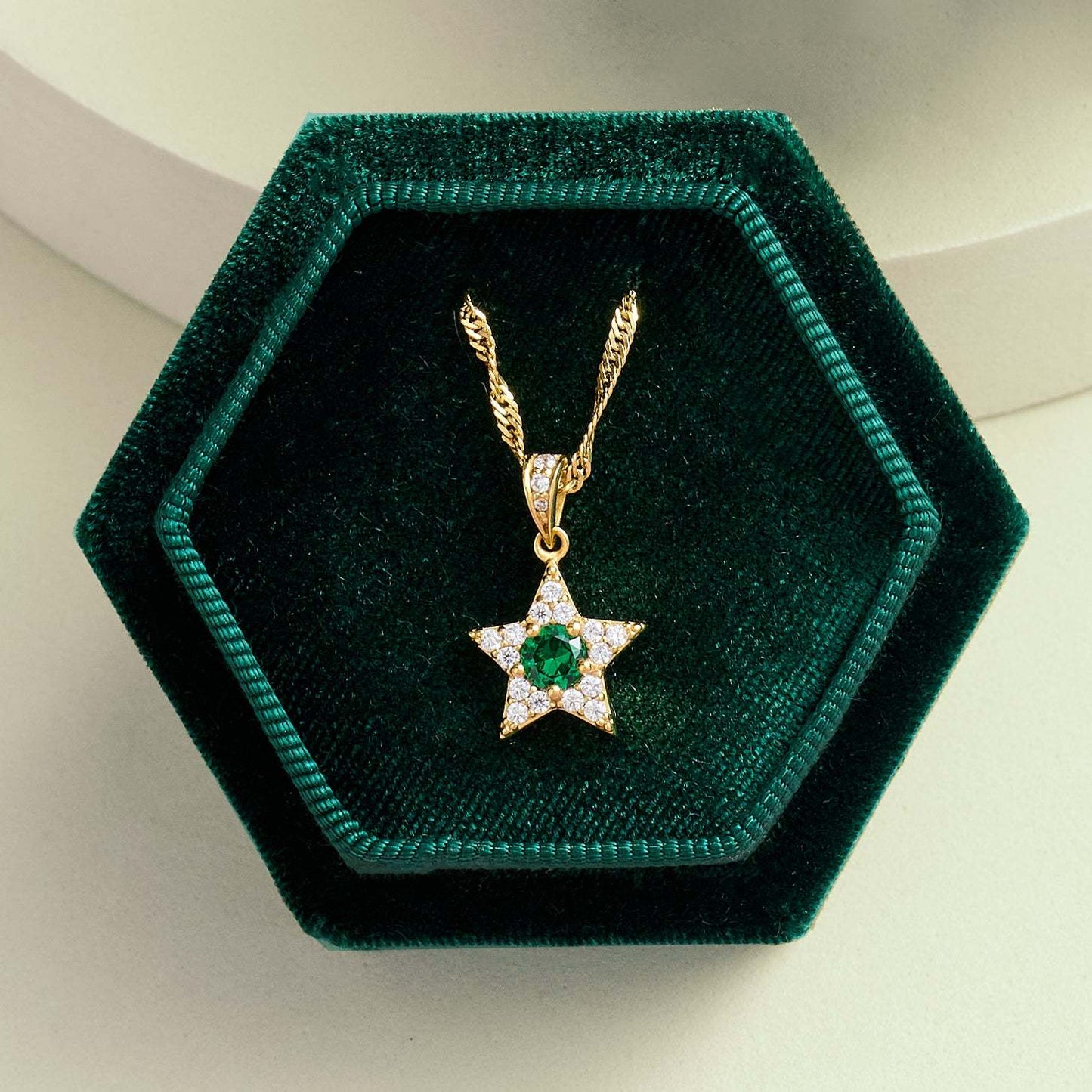 Celeste Mini Star Pendant Necklace with emerald and clear stones in gold plated sterling silver, displayed in green velvet box