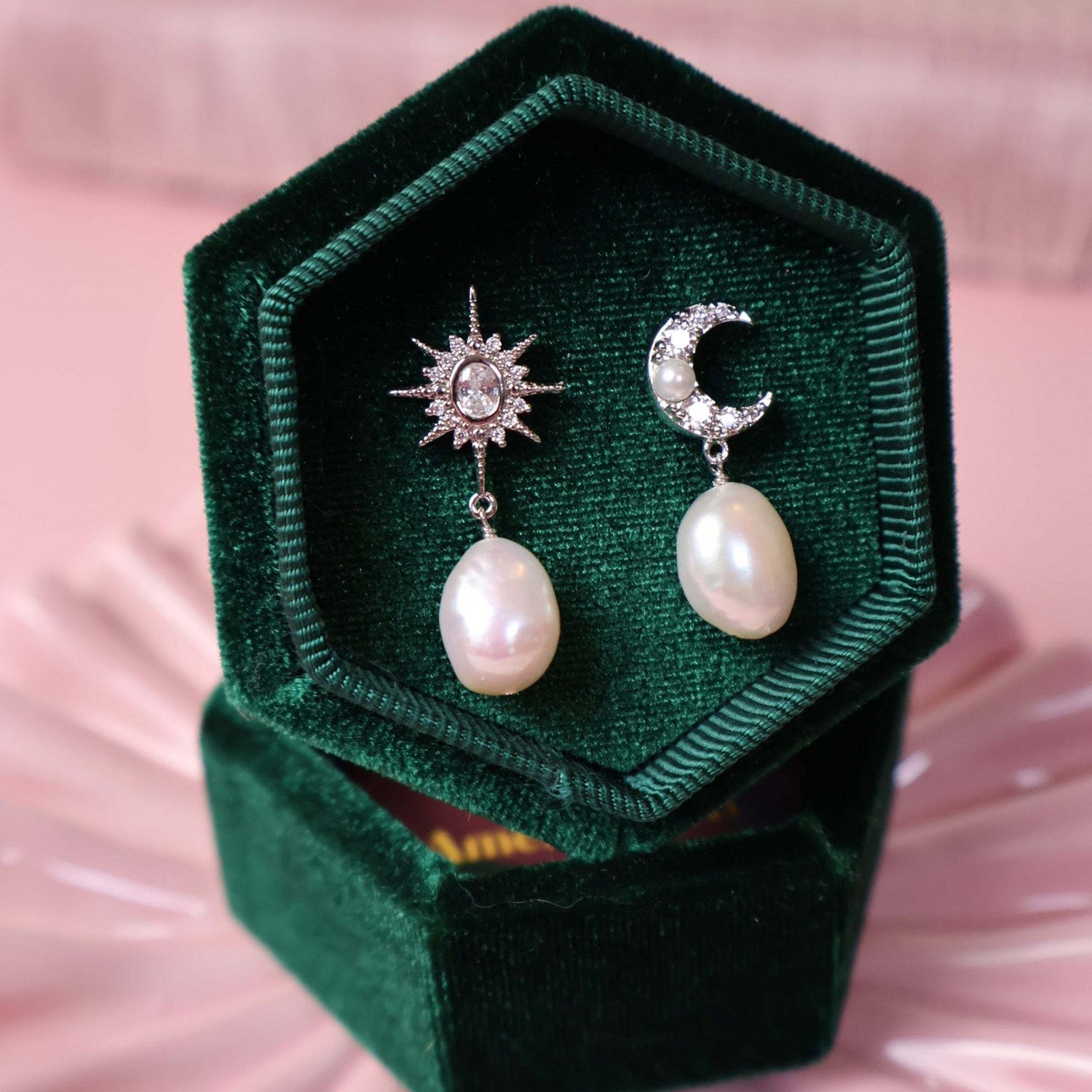 Silver pearl star earrings in a green jewellery box on a pink background