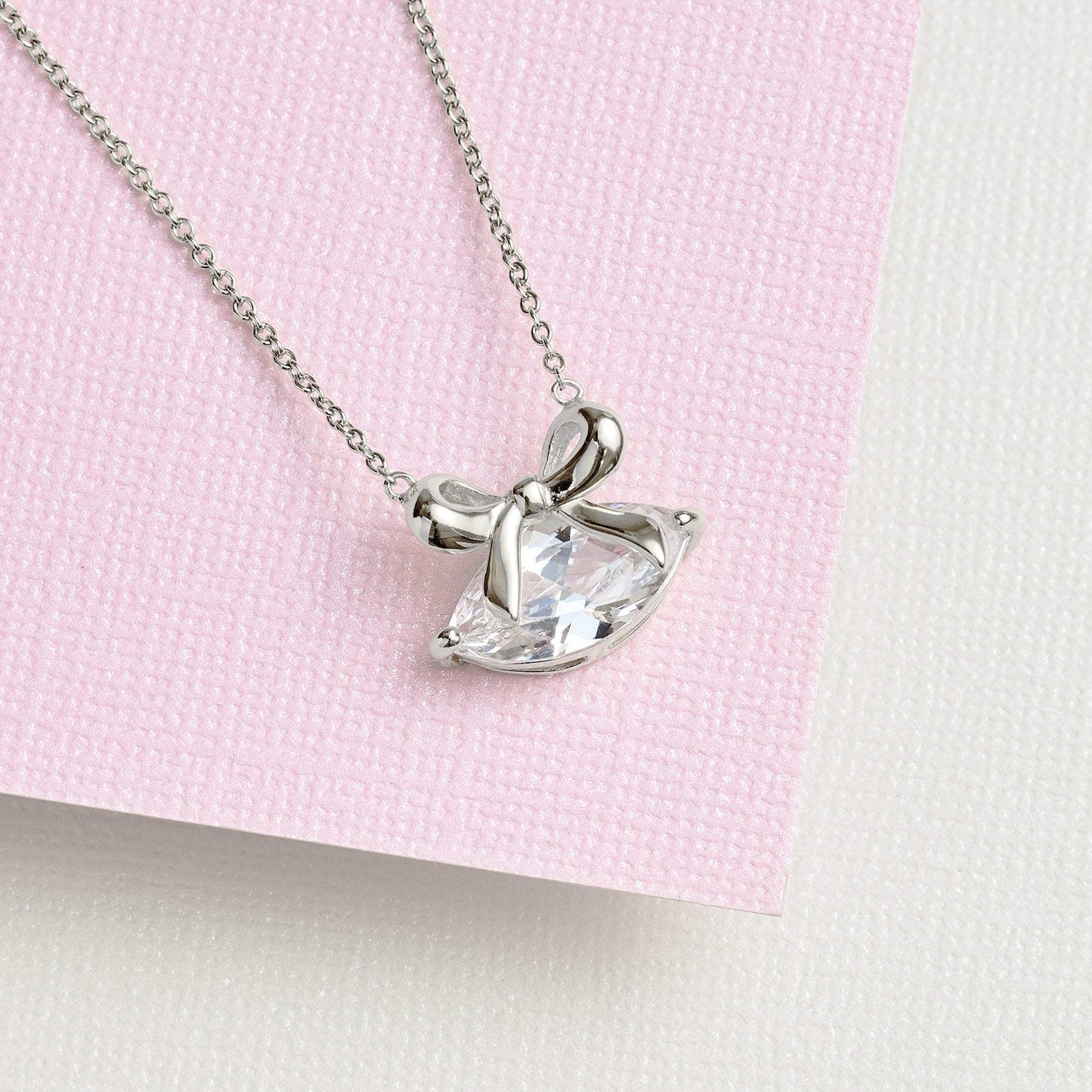 Amelia Bow Necklace silver chain with clear marquise cubic zirconia bow pendant on pink background