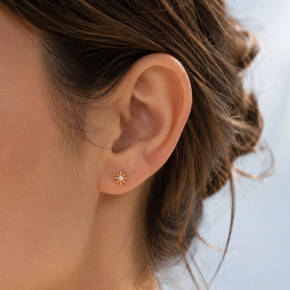 Close-up of an ear wearing a small STAR SHAPED earring with a blurred background